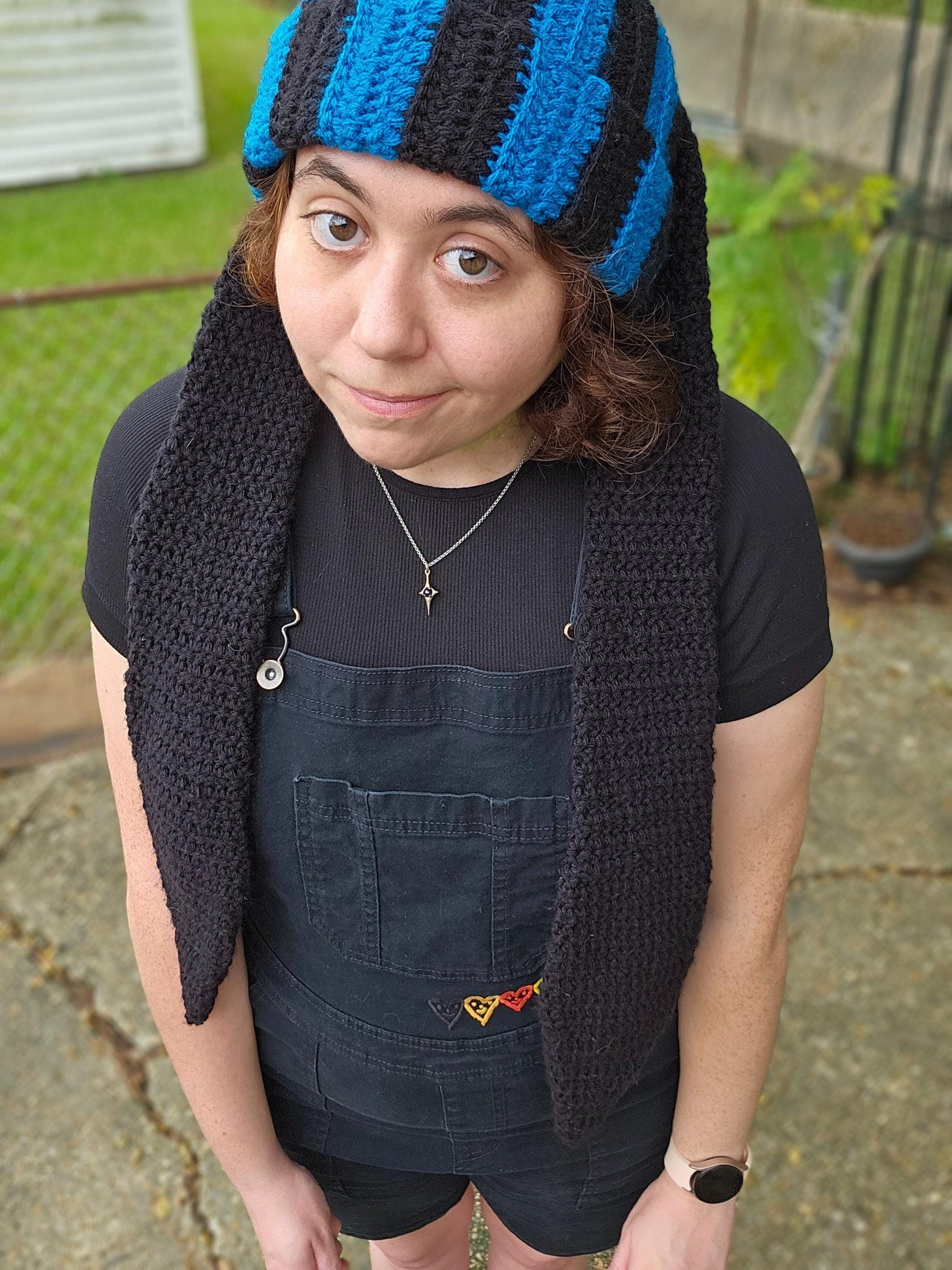 The image features a crocheted beanie with extra long bunny ears in a black and sapphire blue striped pattern; with the ears hanging down.